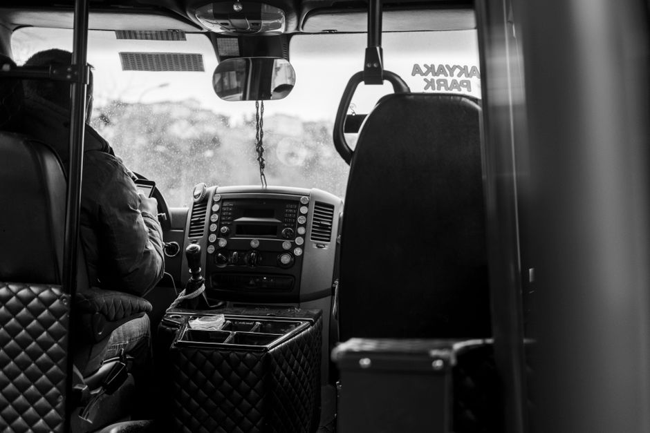 Een buschauffeur in uniform die in een stadsbus zit en passagiers verwelkomt.