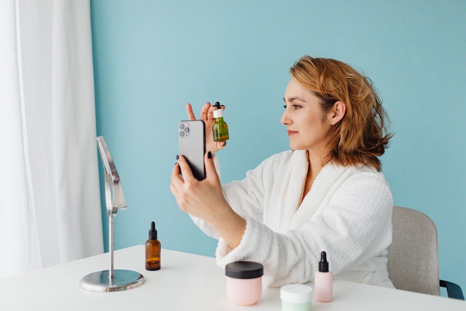 Een vrouw met een stralende huid, omringd door vitamines en technologieën voor huidverzorging.